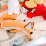 A collection of plush toys on a children's play mat featuring animal designs.